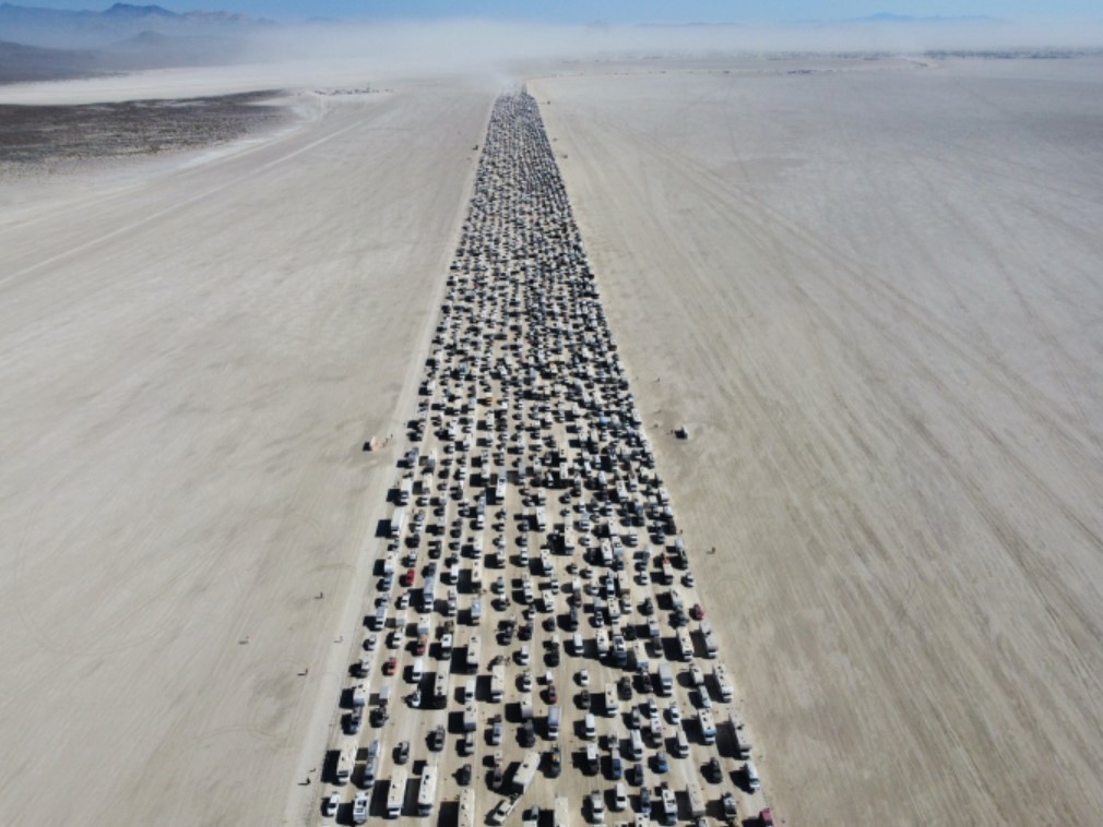 Hàng dài ô tô xếp hàng để ra khỏi lễ hội, hai bên toàn là cát lún.