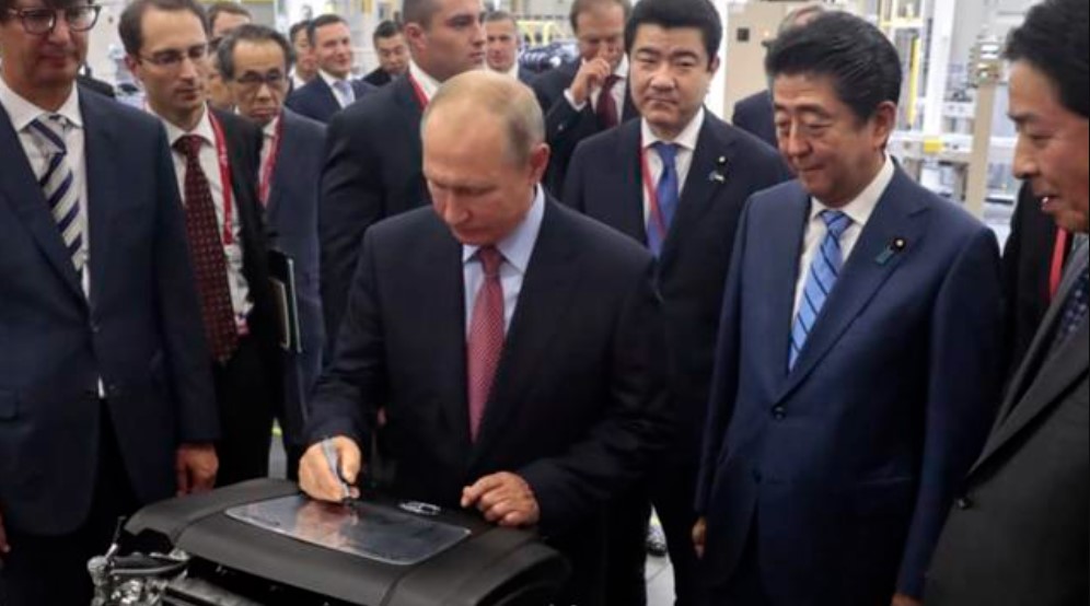 Tổng thống Nga Vladimir Putin ký trên một động cơ vào năm 2018 trong khi thăm nhà máy ô tô Mazda Sollers Manufacturing Rus với cố Thủ tướng Nhật Bản Shinzo Abe ở Vladivostok, Nga. Ảnh: AP.
